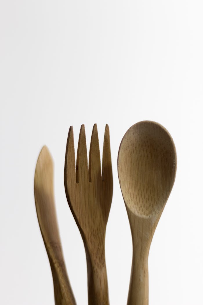 Eco-friendly bamboo cutlery set including a fork, spoon, and knife against a white background.